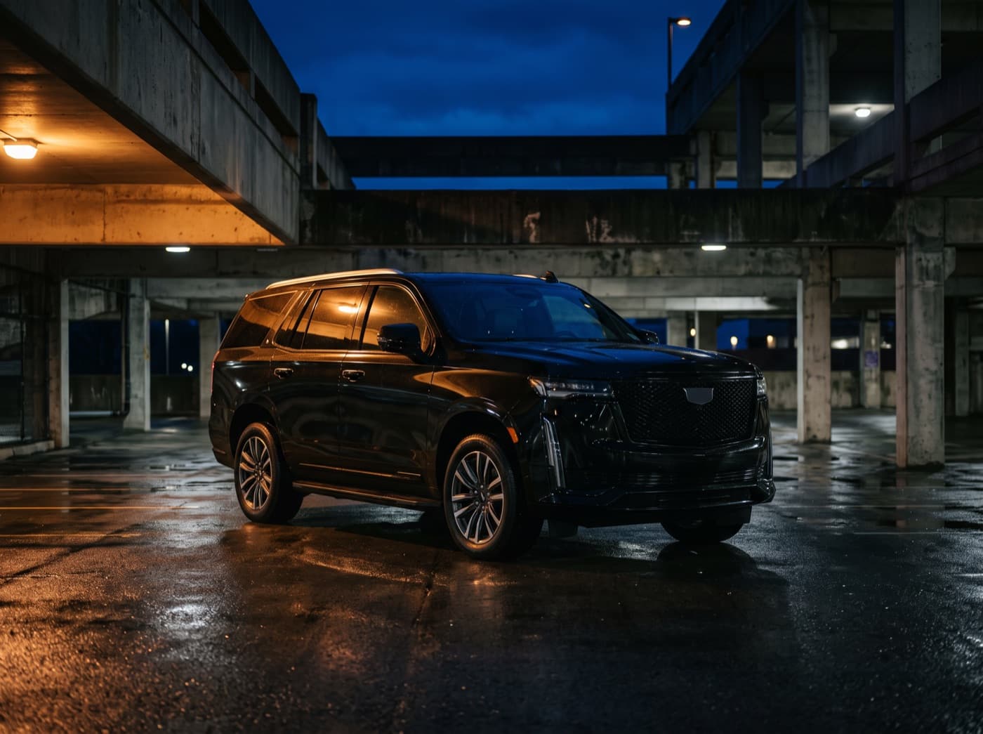 A black full-size luxury SUV parked in a concrete garage at night.